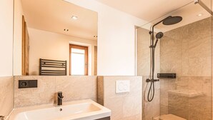 Un baño moderno con lavamanos, inodoro y ducha.
