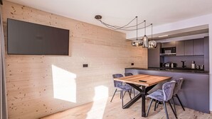 Une cuisine moderne avec un mur en bois, un grand téléviseur à écran plat et des luminaires suspendus.
