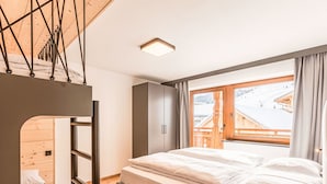 Une chambre avec un lit superposé, une armoire et une fenêtre donnant sur un bâtiment en bois.