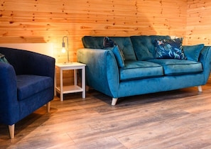 A room with a blue sofa, a small white side table, and a lamp.