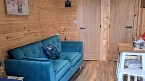 Une pièce avec un canapé bleu, une porte en bois, une petite table et une chaise blanche.
