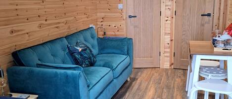 A room with a blue sofa, a wooden door, a small table, and a white chair.