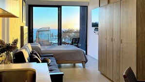 A modern bedroom with a large bed, a balcony with a view of the sea, and a sliding wardrobe.
