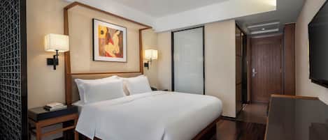 A modern hotel room with a large bed, two bedside tables with lamps, a flat-screen TV, and a painting on the wall.