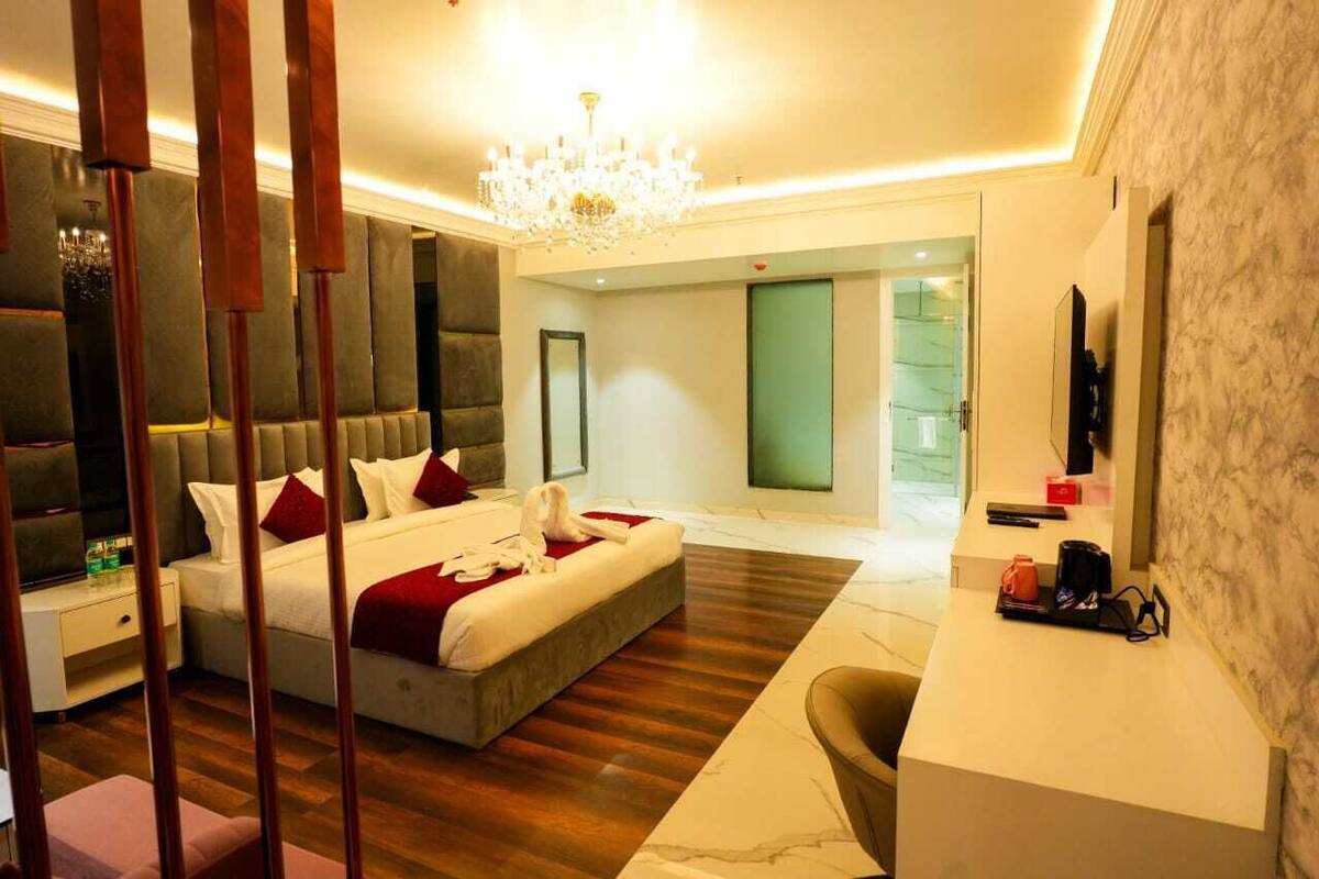 Une chambre d’hôtel moderne, dotée d’un grand lit, d’un bureau et d’un lustre.