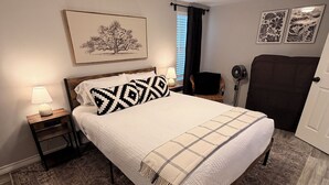 A bedroom with a bed, a nightstand, a lamp, a chair, a radiator, and artwork on the walls. - Chic 1-bedroom apartment in  Springtown, TX with AC, WiFi (Springtown)
