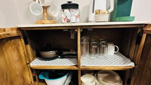 A kitchen with wooden shelves holding dishes, a coffee maker, and a kettle. - Chic 1-bedroom apartment in  Springtown, TX with AC, WiFi (Springtown)