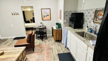 A compact living space with a kitchenette, a dining area, and a seating area with a sofa and a coffee table.