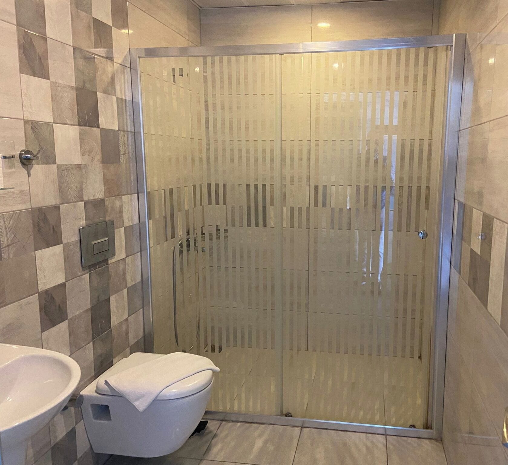 Un baño con ducha de vidrio, inodoro blanco y lavamanos.