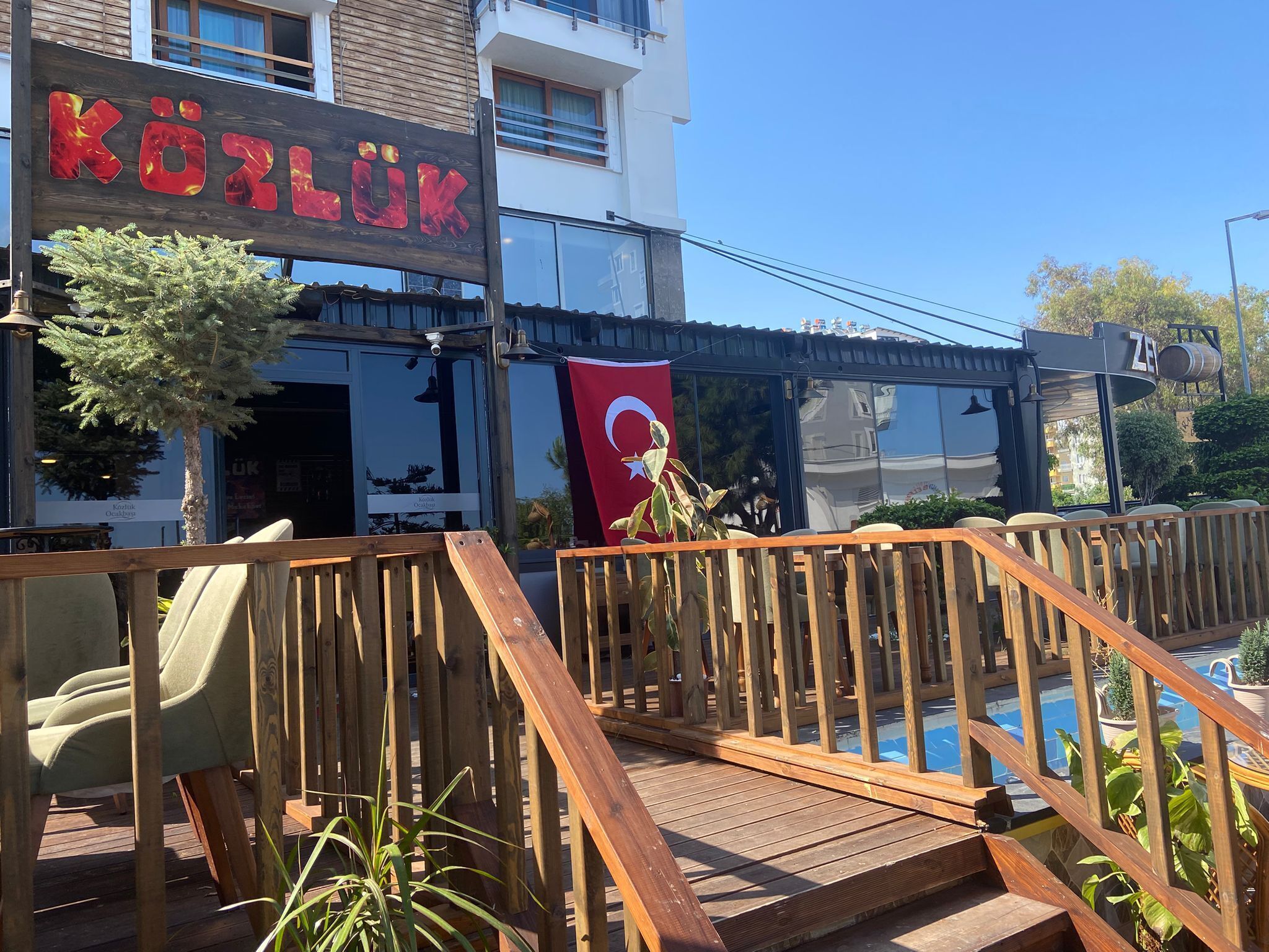 A wooden deck with a pool, a sign reading "KÖLÜK", and a Turkish flag.