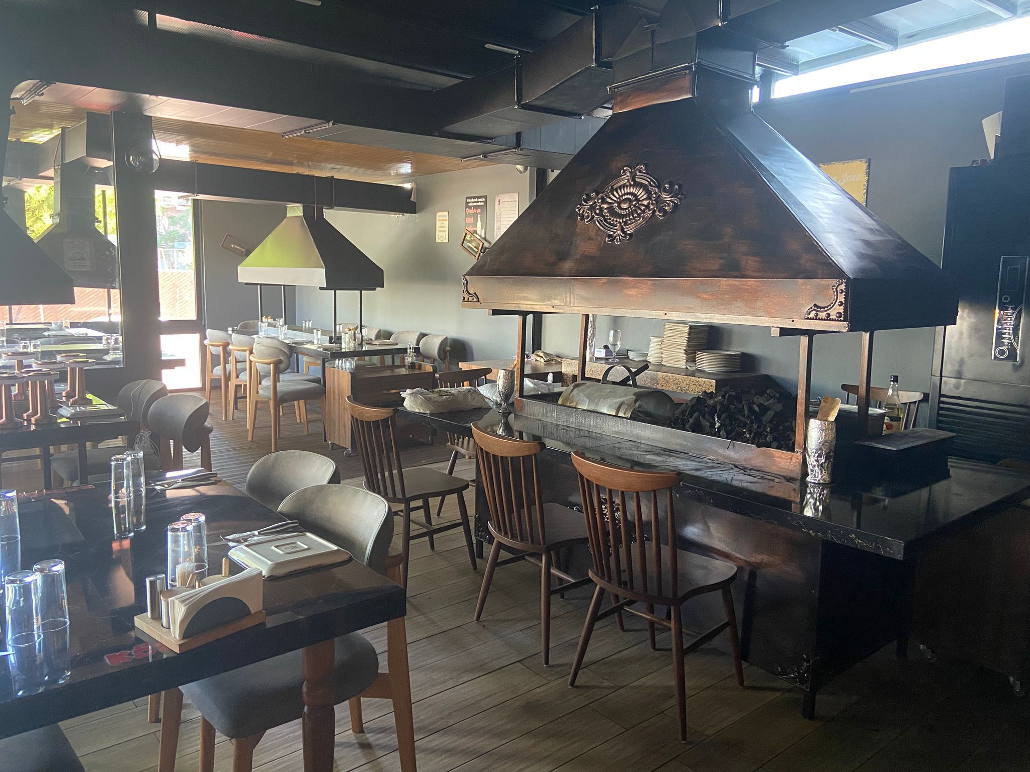 A restaurant with a central bar area, wooden chairs, and a large decorative chimney.