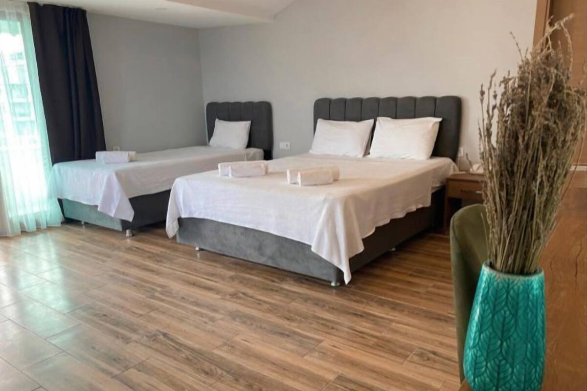 Una habitación de hotel con dos camas, suelo de madera y un jarrón decorativo.