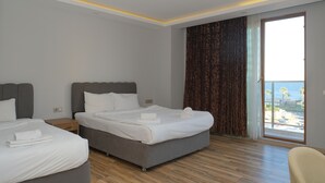 Habitació d'hotel amb dos llits, una finestra gran i vistes, i un balcó.