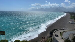 Vistes costaneres amb una platja, ones i muntanyes al fons.