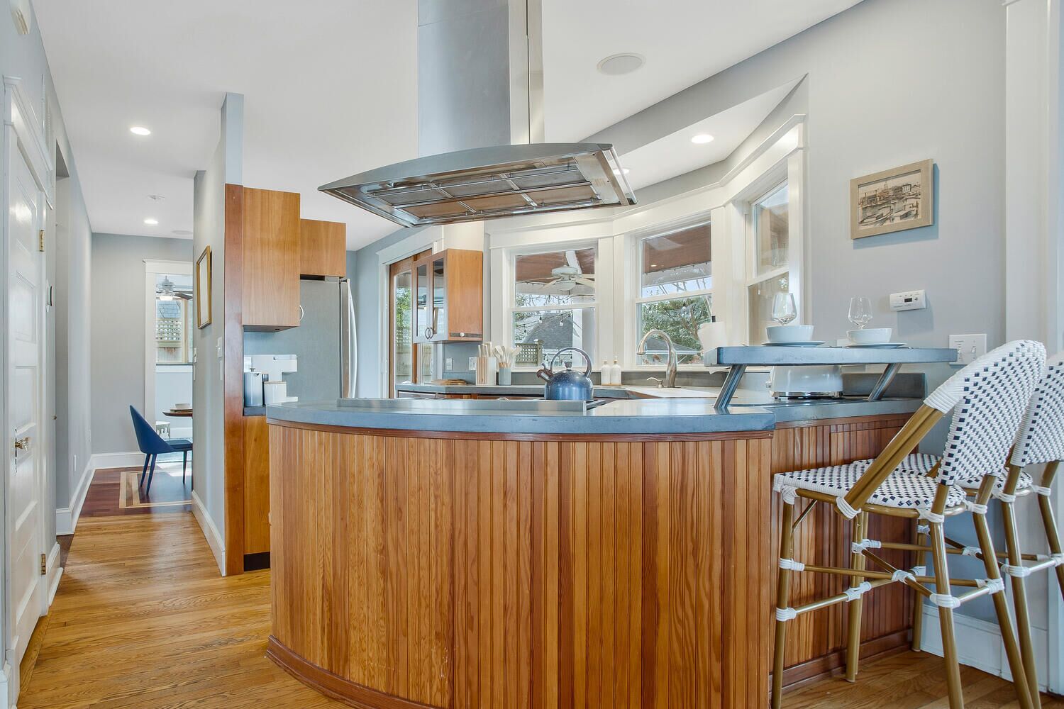 A modern kitchen with a wooden island, a built-in stove, and a window overlooking the garden.