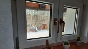 A window with a view of a wooden deck and a hot tub. There are three potted cacti on the windowsill. - Vacation home Rötzer - Forsthausschmankerl (Bruck in der Oberpfalz)