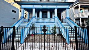 Una casa a due piani con un portico, una scala e un piccolo giardino.