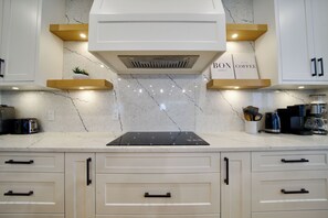 Een moderne keuken met witte kasten, een zwart aanrecht en een ingebouwde kookplaat.