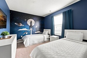 A bedroom with two beds, a nightstand, a dresser, a wall mural of space, and a window with curtains. - Stunning 10 Bed Home with Themed Rooms, Pool (Clermont)
