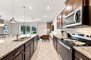 Eine moderne Küche mit Granit Arbeitsplatten, Edelstahlgeräten und einer großen Kochinsel mit Sitzgelegenheiten.
