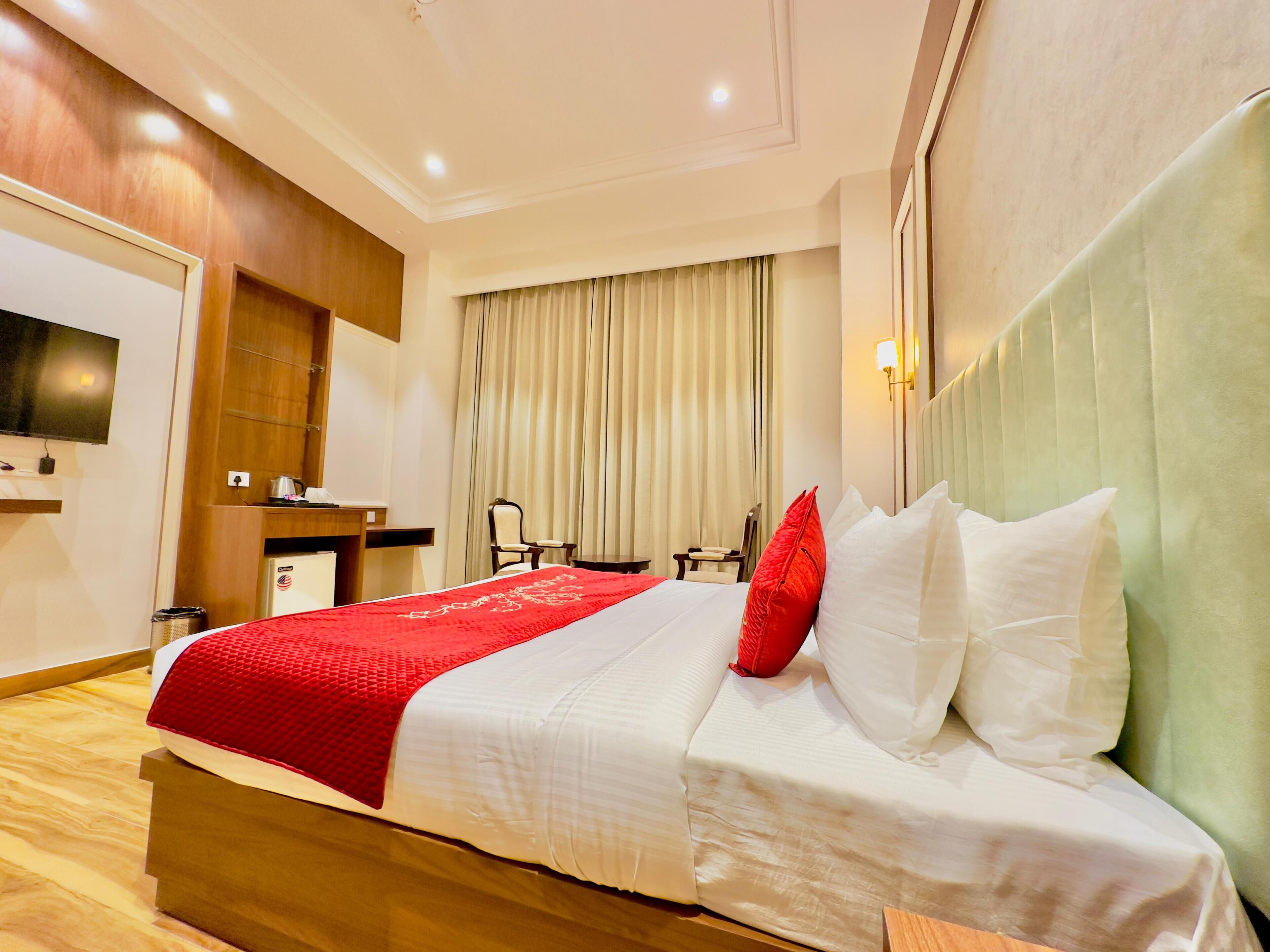 A hotel room with a bed, a desk, a chair, a television, and a window with curtains.