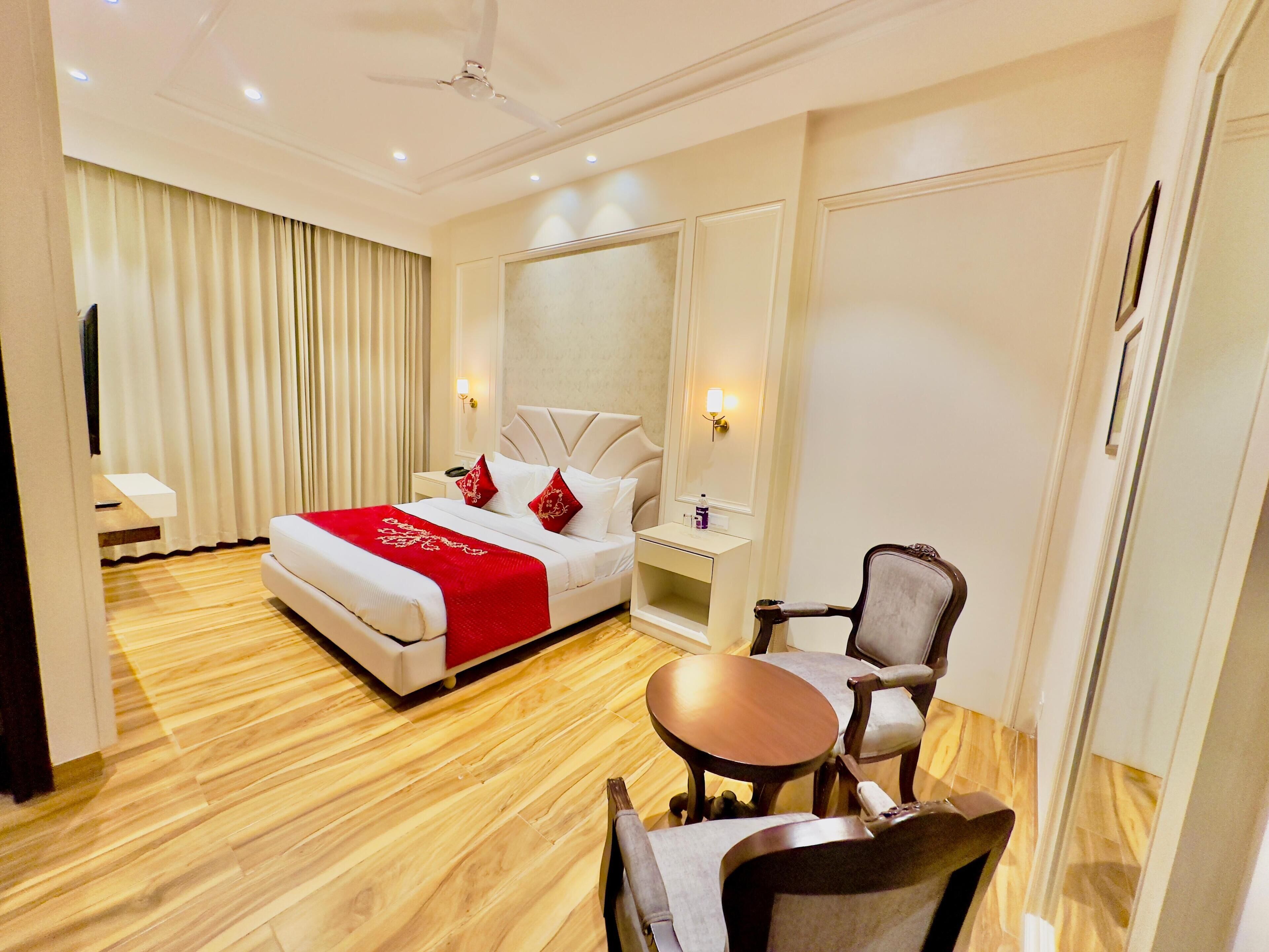 A hotel room with a bed, bedside table, chair, and a small table.