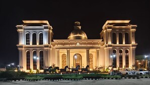 A grand building with a central dome and symmetrical wings, illuminated at night. - HOTEL SUKH FARM (Sangrur)
