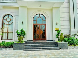A building with a grand entrance featuring a large arched doorway, steps leading up to it, and a sign indicating 'Sukh Farm'. - HOTEL SUKH FARM (Sangrur)