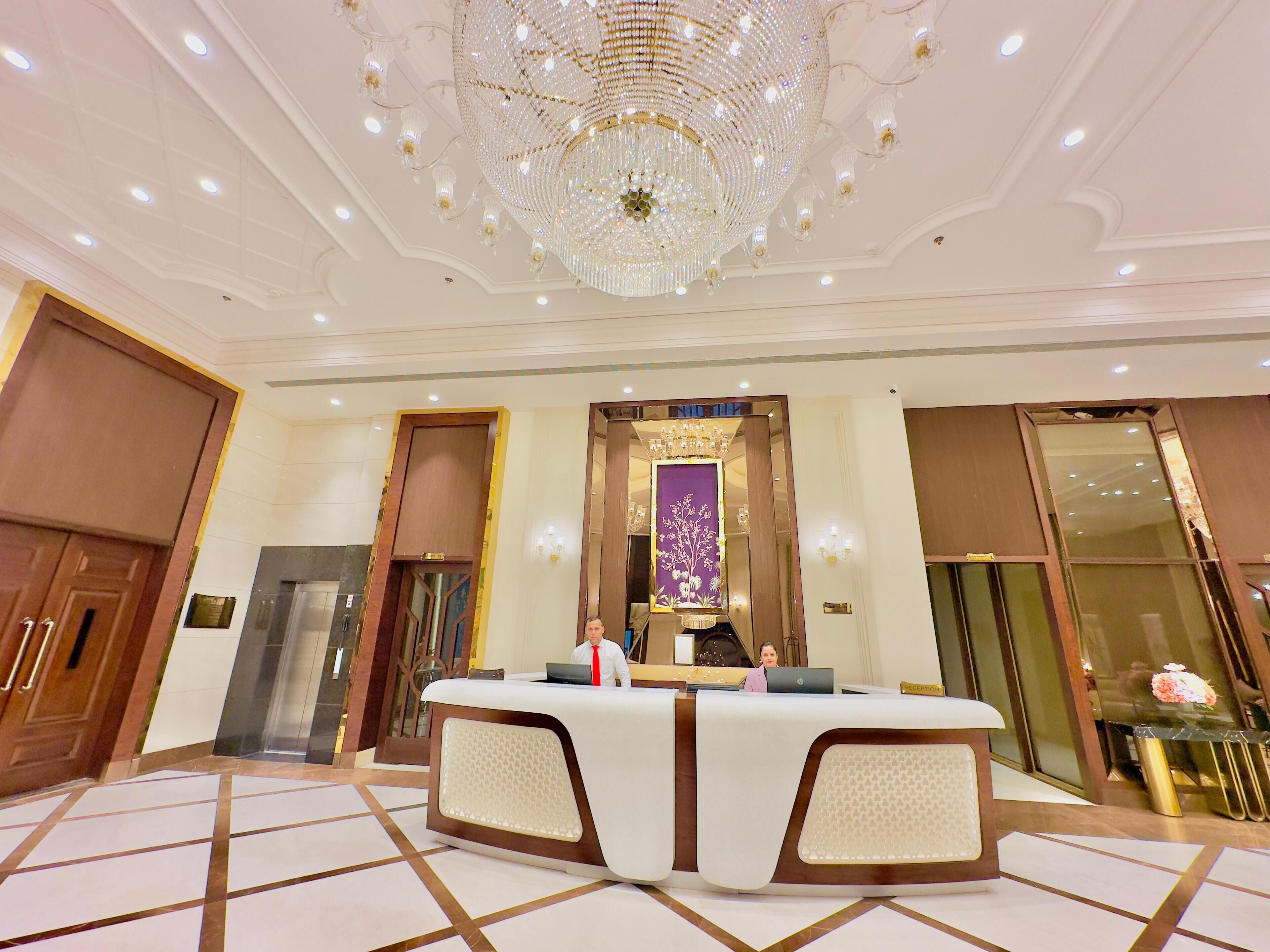 A reception area with a marble floor, a large chandelier, and a reception desk.