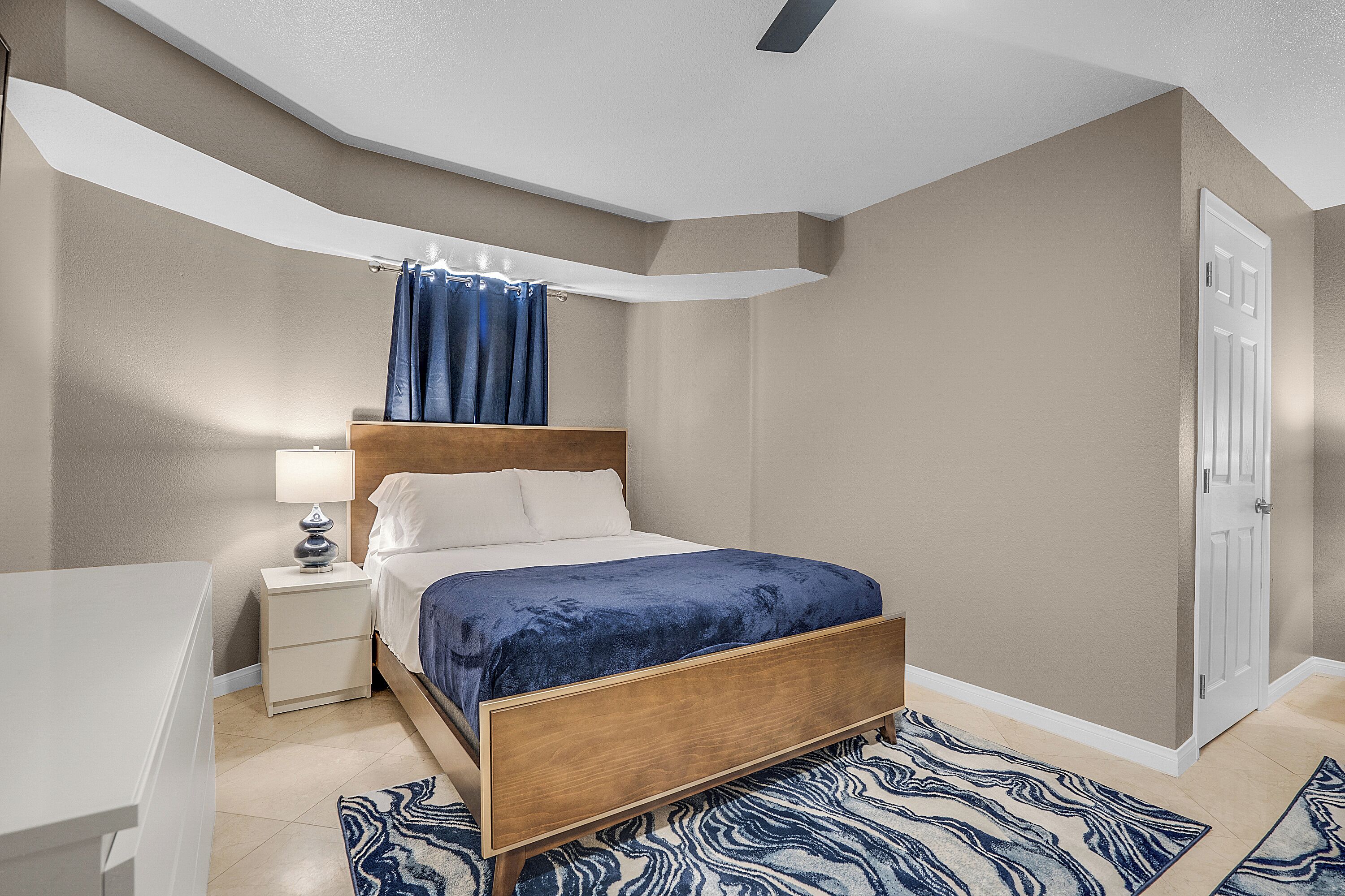 A bedroom with a bed, nightstand, and a door.