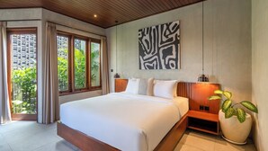 Un dormitorio moderno con una cama grande, cabecera de madera y vistas a la vegetación a través de amplios ventanales.