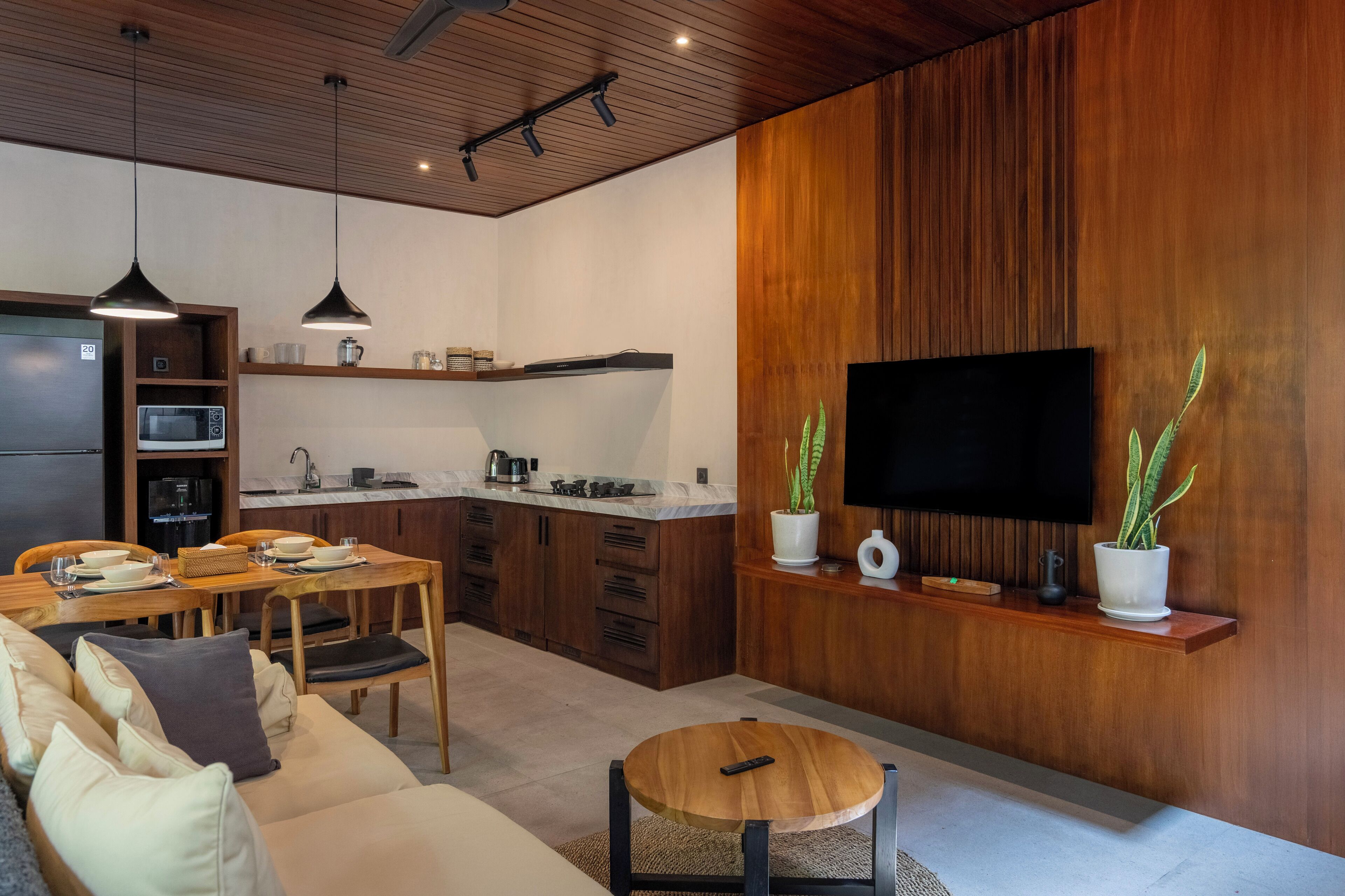 Een moderne keuken met houten kastjes, een inbouwmagnetron en een eethoek met een houten tafel en stoelen.
