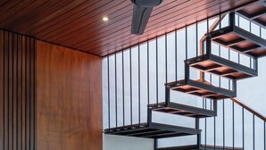 Una sala moderna con techo de madera, televisor de pantalla plana, sofá, mesa de centro y una escalera de caracol.