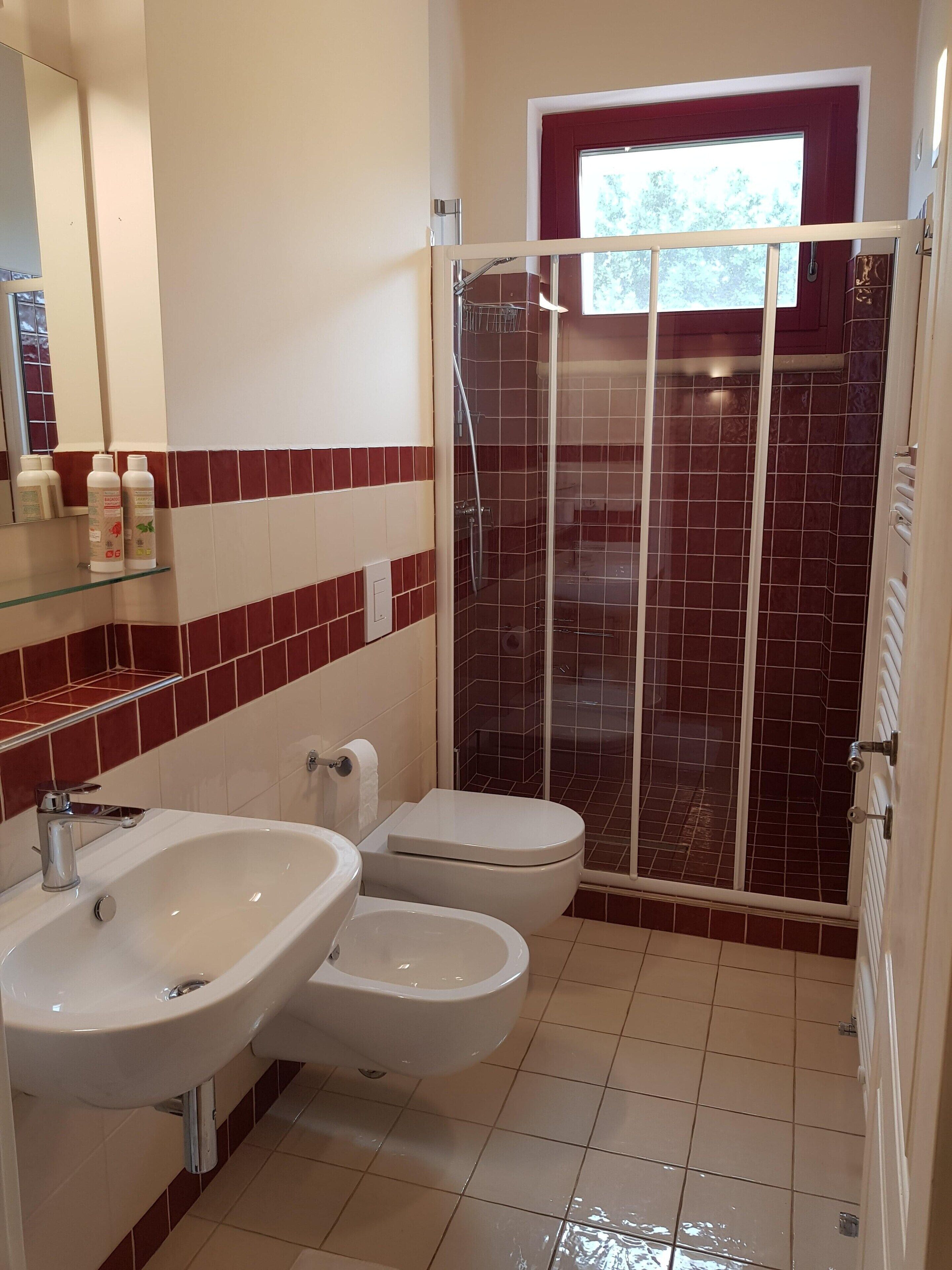 A bathroom with two sinks, a toilet, and a shower enclosure.