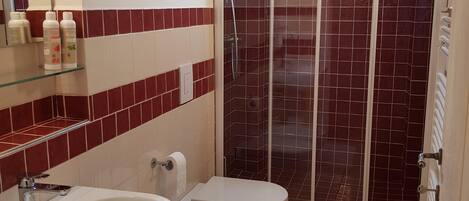 A bathroom with two sinks, a toilet, and a shower enclosure.