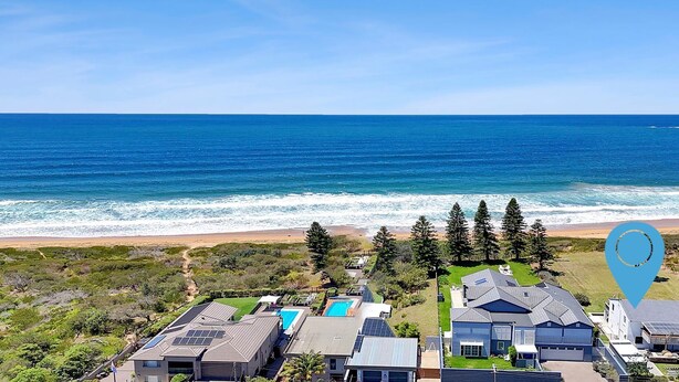 A coastal residential area with houses, a swimming pool, and a view of the ocean.