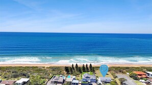 A coastal residential area with houses, a beach, and a clear view of the ocean.