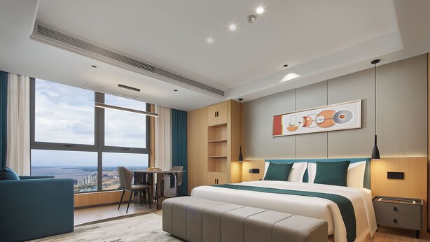 Ett modernt hotellrum med en stor säng, ett skrivbord och utsikt över staden.