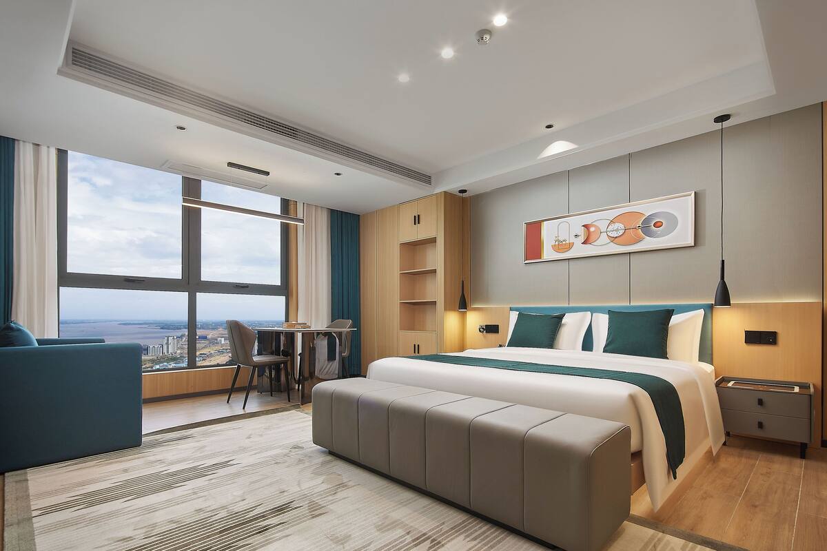Een moderne hotelkamer met een groot bed, een bureau en uitzicht op de stad.