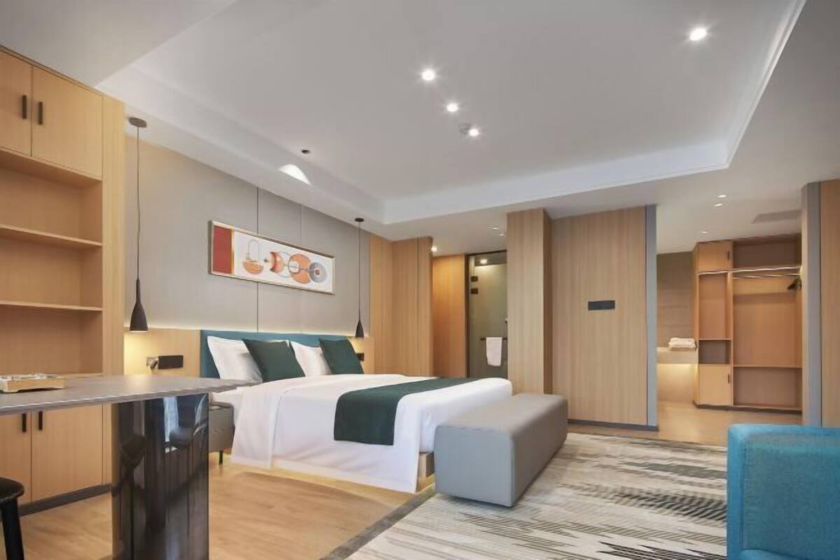 Een moderne hotelkamer met een bed, een bureau, een stoel en een kledingkast.