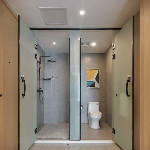 A modern bathroom with a glass-enclosed shower, a toilet, and a painting on the wall. - ALL IN LIGHT LUXURY HOTEL (Phnom Penh)