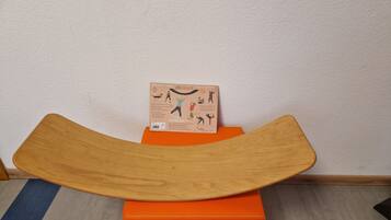 A wooden bench with a curved backrest on an orange ottoman.