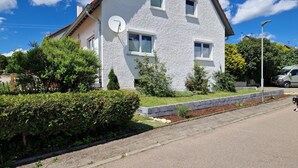 Una casa de dos pisos con antena parabólica, césped bien cuidado y entrada pavimentada.