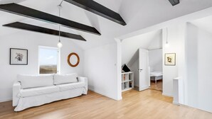 A spacious living area with a white sofa, wooden flooring, and a large window offering a view. - "Laurentia" - 200m from the sea by Interhome (Harboøre)