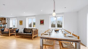 A spacious living room with a wooden dining table, a sofa set, and a bookshelf. - "Laurentia" - 200m from the sea by Interhome (Harboøre)