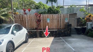A parking area with a white car parked, marked with 'PR' for reserved parking. - Kona Polynesian King - Tropical Island Soul (Kailua-Kona)