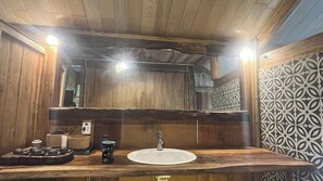 Un baño de madera con un espejo grande, un lavamanos y una pared con azulejos estampados.