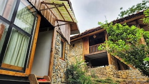 Un edificio rústico de piedra con un balcón de madera y un ventanal grande.