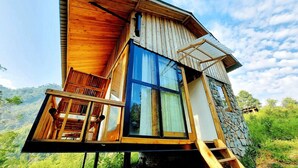 Una casa moderna de madera con balcón, ventanas amplias y una pared de piedra.