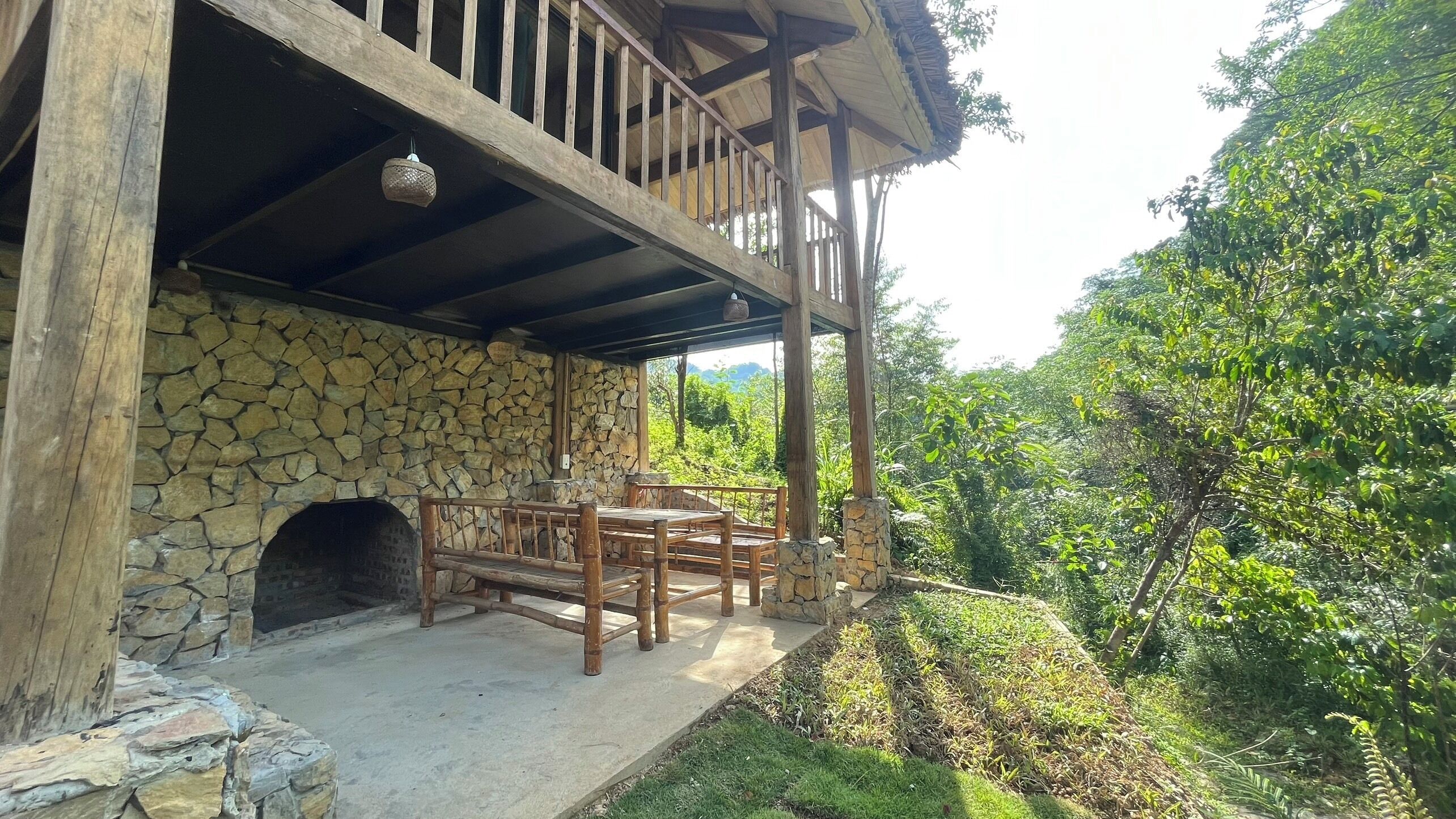 Un bâtiment en pierre doté d’un porche en bois et d’une cheminée en pierre.